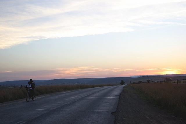 Boys riding a bike at sunset
