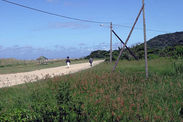 Two people walking on dirt road